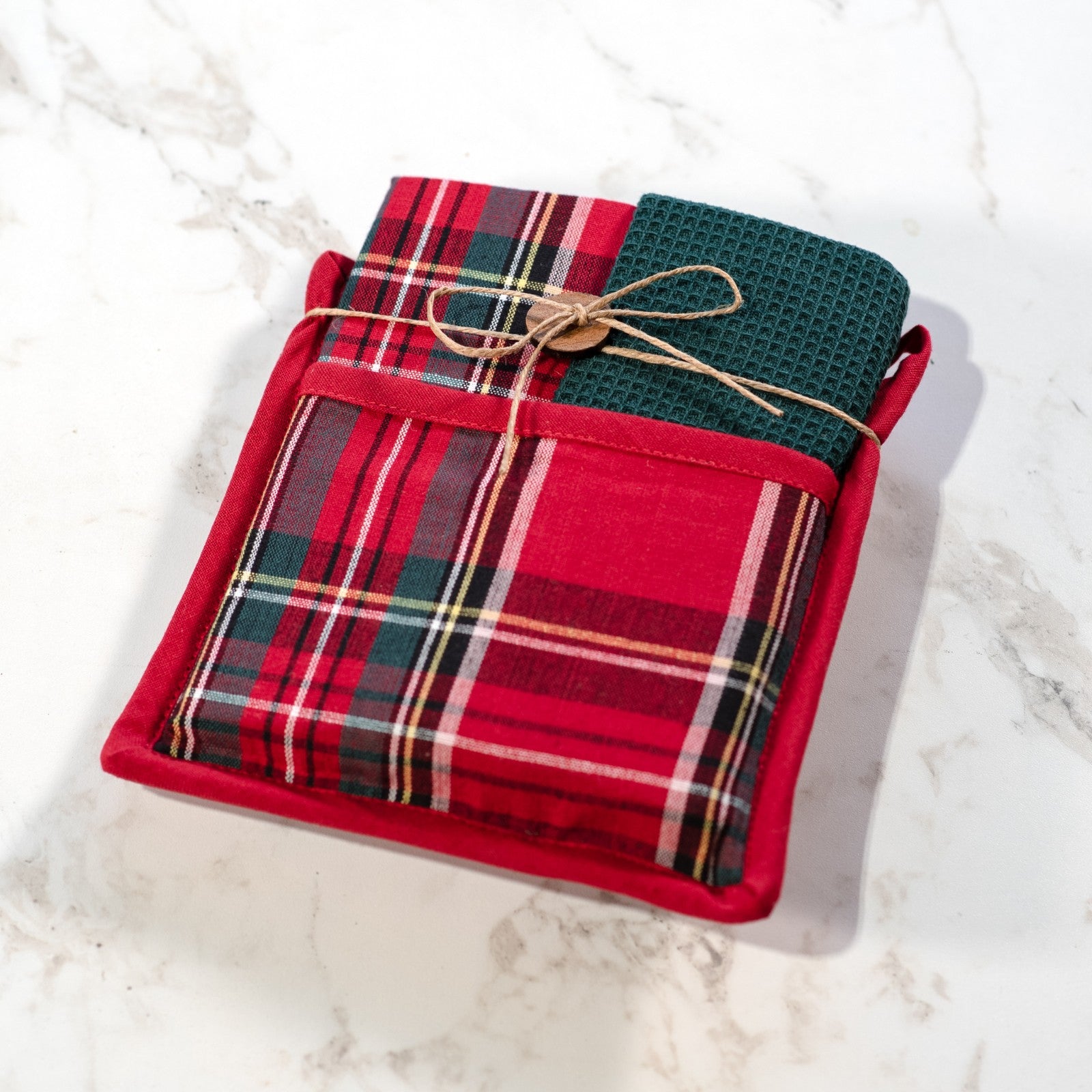 Red tartan plaid potholder with a pocket holding a folded green waffle towel tied with twine