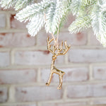 Tiny gold metal reindeer ornament with branching antlers hanging from a frosted pine branch