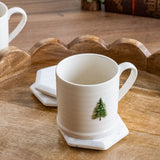 Cream ribbed ceramic mug with a small raised green Christmas tree, set on a white hexagon coaster