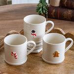 Three cream ceramic mugs with raised snowman, candy cane and gingerbread man accents on a wood tray