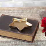 Small gold star-shaped dish resting on top of a vintage leather-bound book
