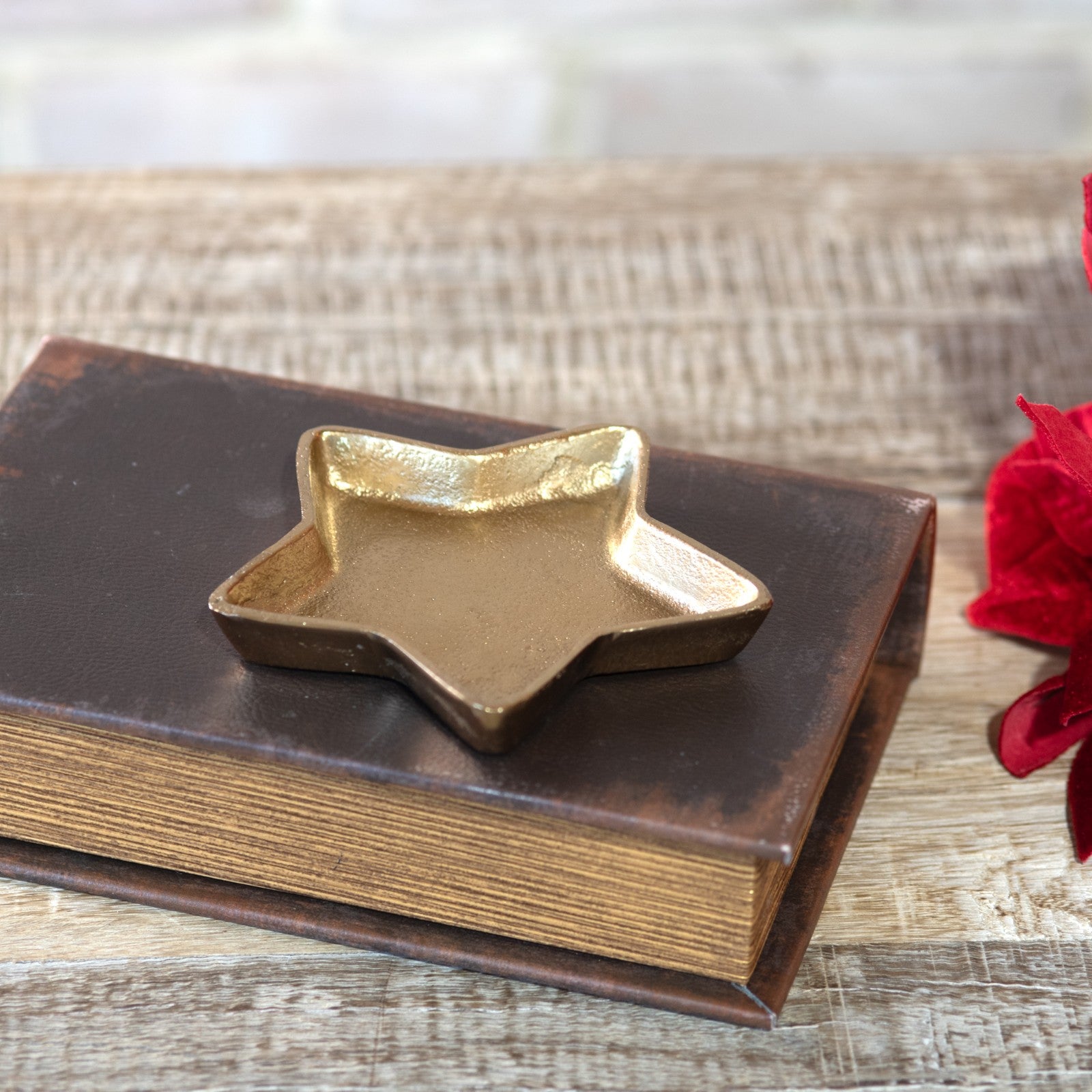 Small gold star-shaped dish resting on top of a vintage leather-bound book