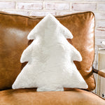 White faux fur Christmas tree-shaped pillow on a cognac leather chair