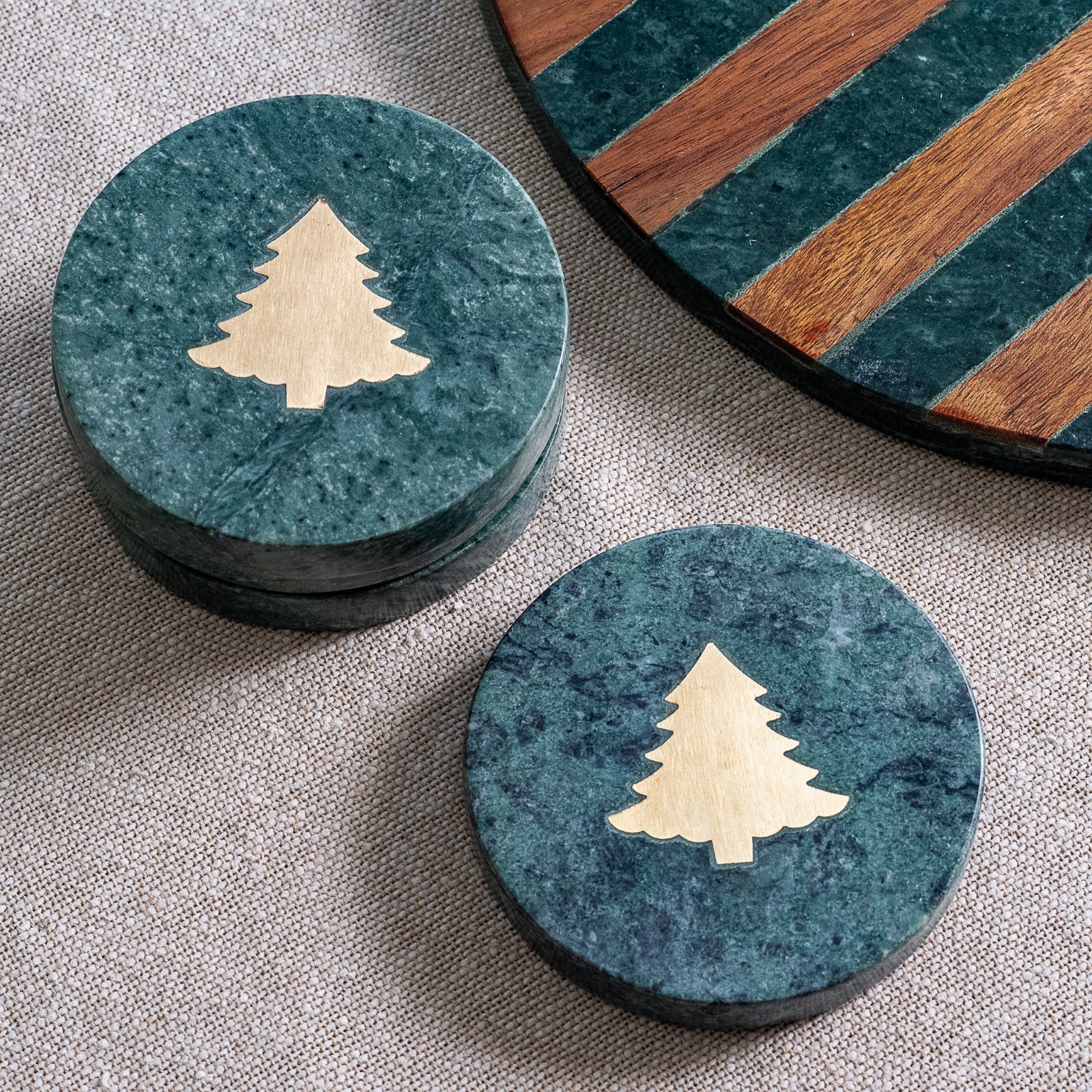 Round green marble coasters inlaid with a gold Christmas tree, shown stacked and single