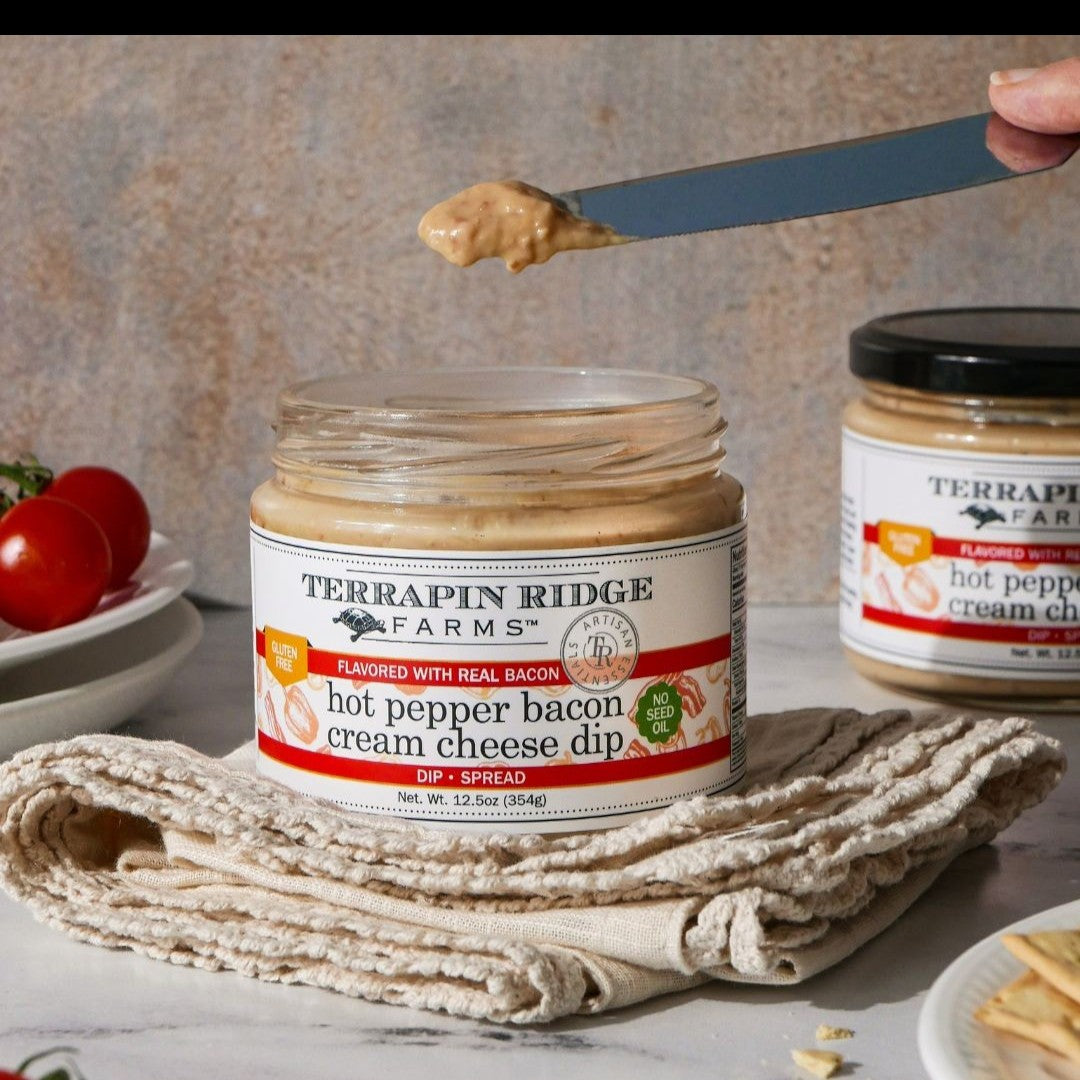 Hot Pepper Bacon Cream Cheese Dip being spread with a knife, fresh tomatoes in background