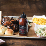 Grilled short ribs with rolls, mac and cheese, pickles and coleslaw beside Hot Pepper Bacon Grill & Wing Sauce