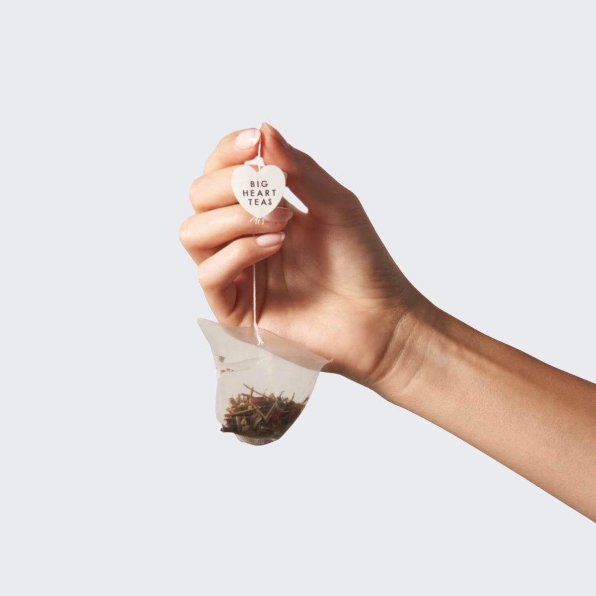 Hand holding a Big Heart Tea compostable Minty Blue tea bag