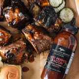 Saucy grilled ribs with pickles and bread next to Hot Pepper Bacon Grill & Wing Sauce