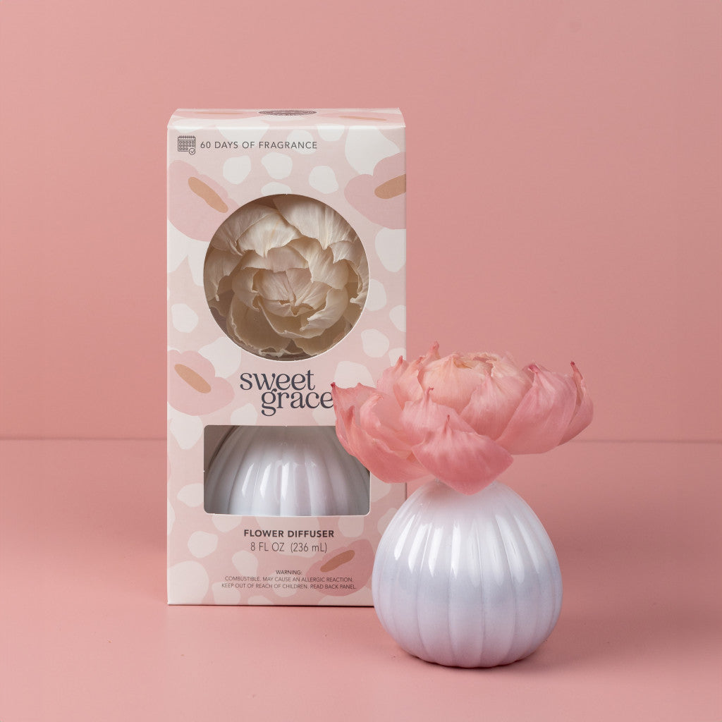 Sweet Grace Flower Diffuser white ceramic base with pink flower in front of pastel pink floral packaging