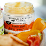 Open jar of Hatch Chile Bacon Ranch Dip with sliced bell peppers and crackers