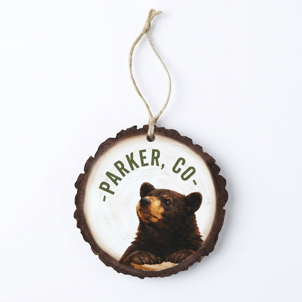 Round wood-slice ornament with a black bear and curved town name, hung on jute twine