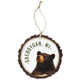 Round wood-slice ornament with a black bear and curved town name, hung on jute twine