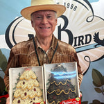 Man in a straw hat holding two boxed bird seed Christmas trees