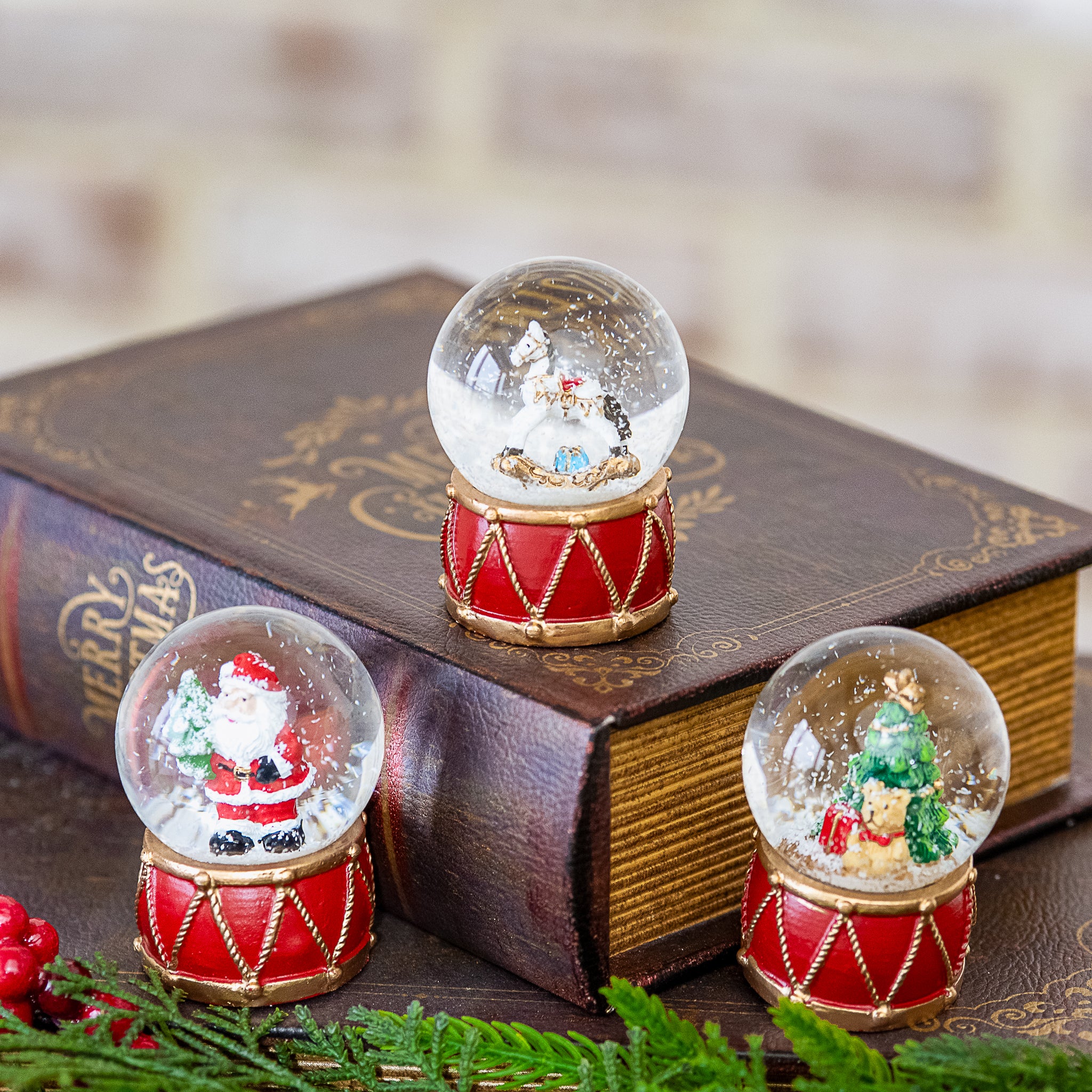 Santa, tree and horse mini snow globes on red drum bases