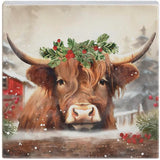 Small square block sign of a Highland cow in a holly crown beside a red barn