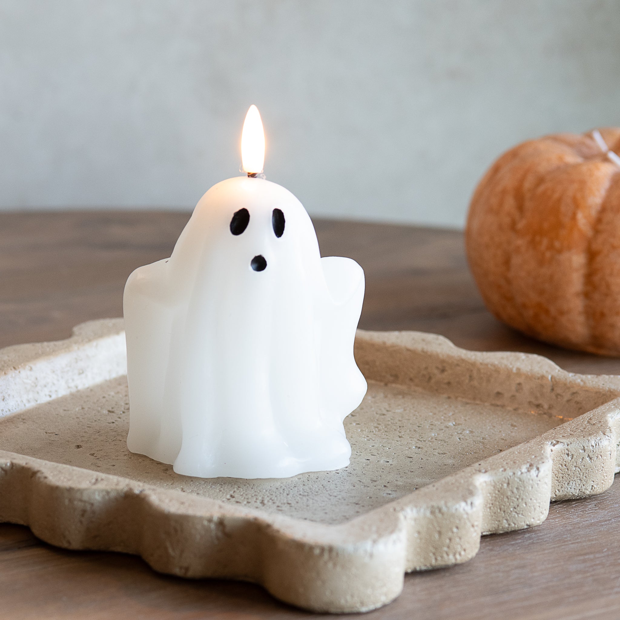 White wax ghost LED candle on a scalloped tray