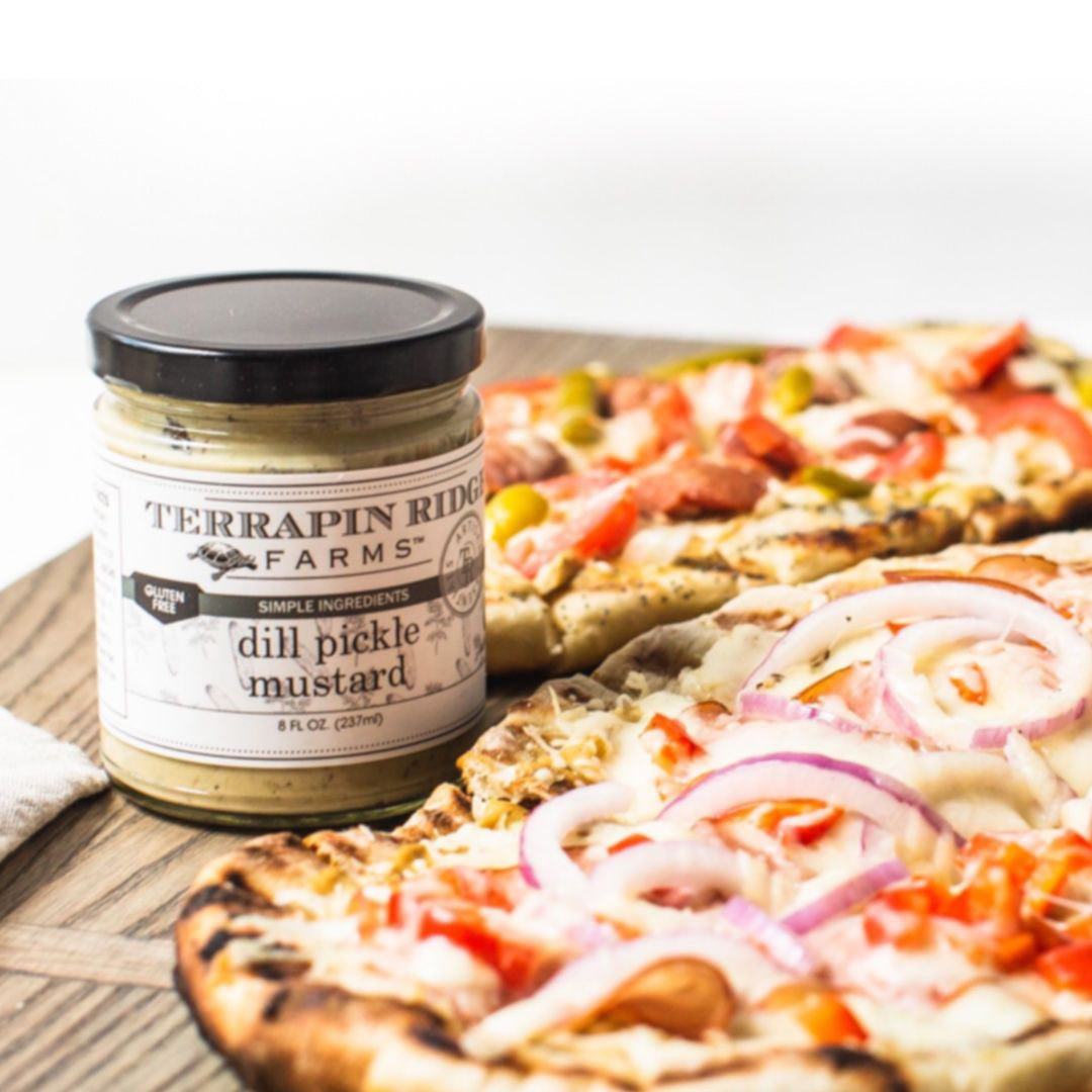 Flatbread pizzas with vegetables beside a jar of Dill Pickle Mustard
