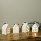 White ceramic LED house ornaments glowing on a wood shelf