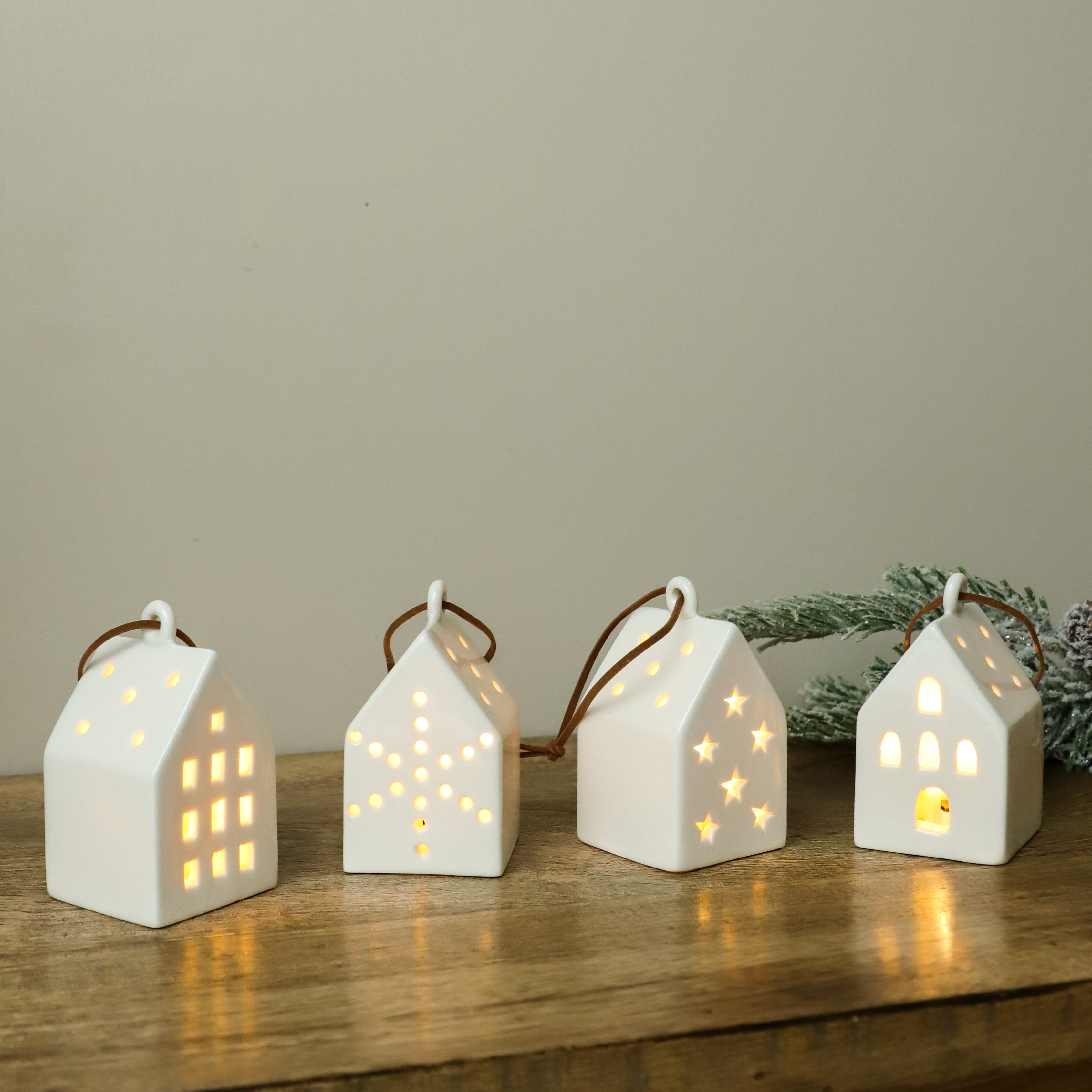 White ceramic LED house ornaments glowing on a wood shelf
