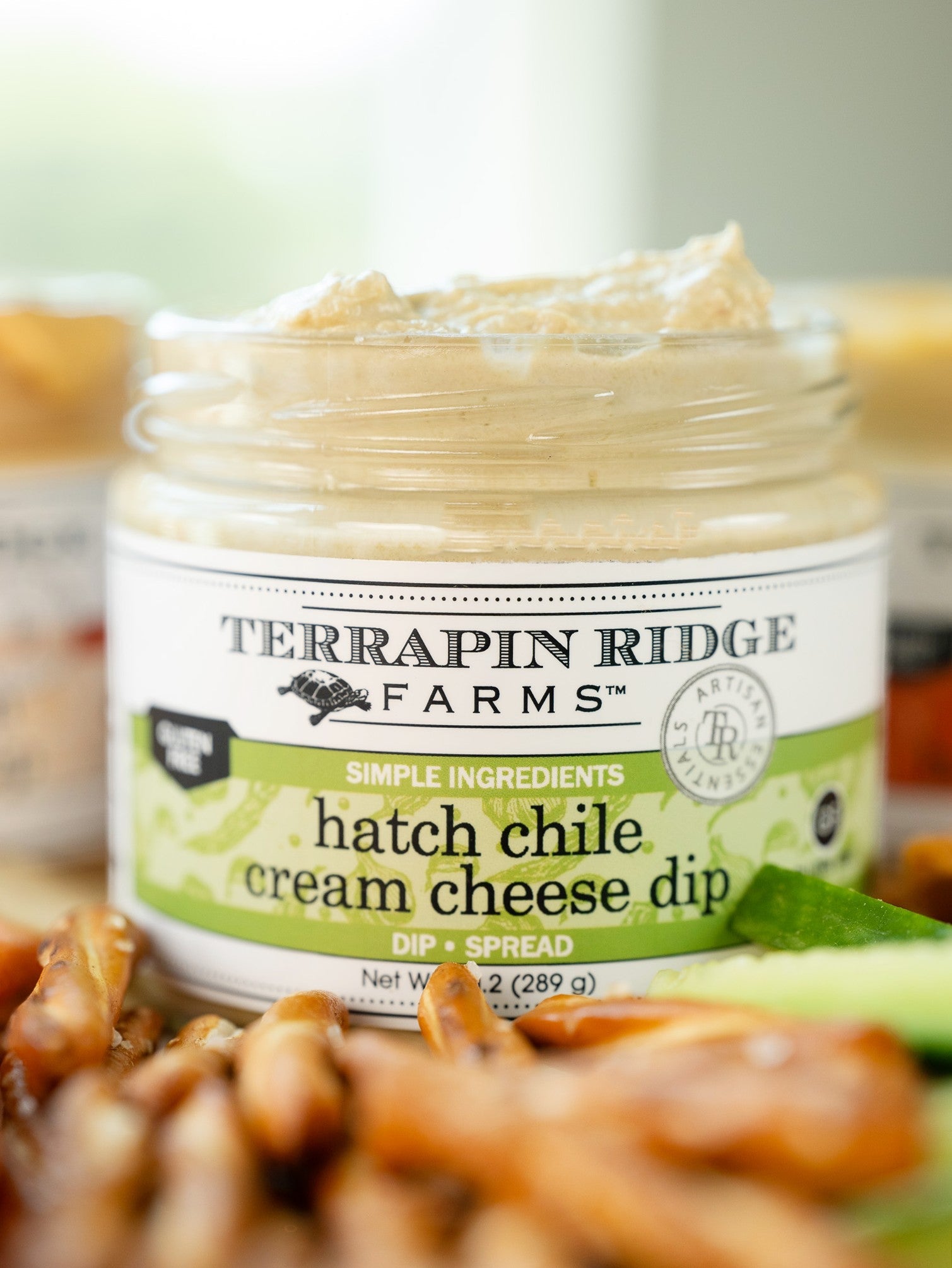 Open jar of Hatch Chile Cream Cheese Dip with pretzels