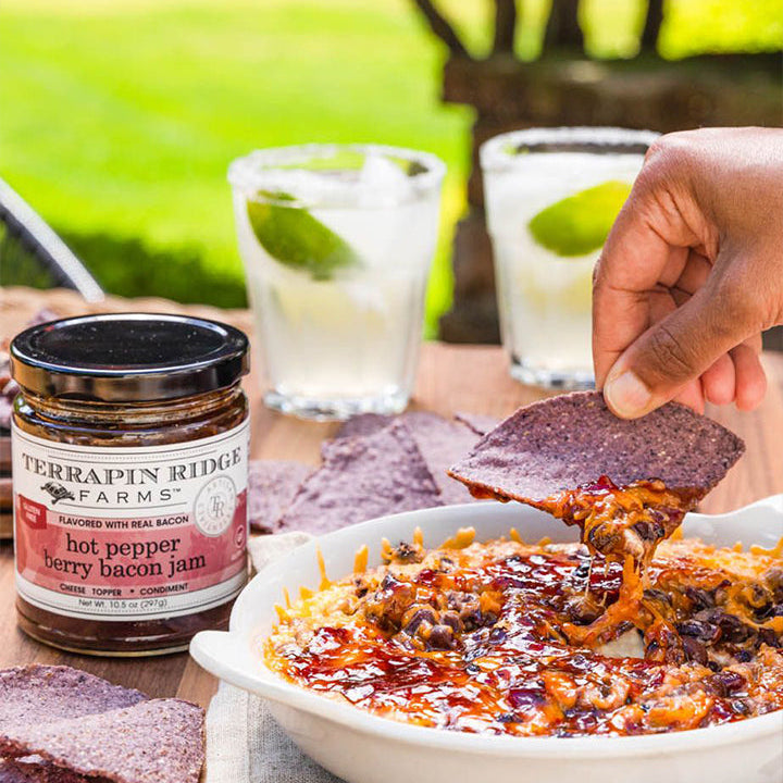 Baked cheese dip topped with Hot Pepper Berry Bacon Jam served with blue corn chips