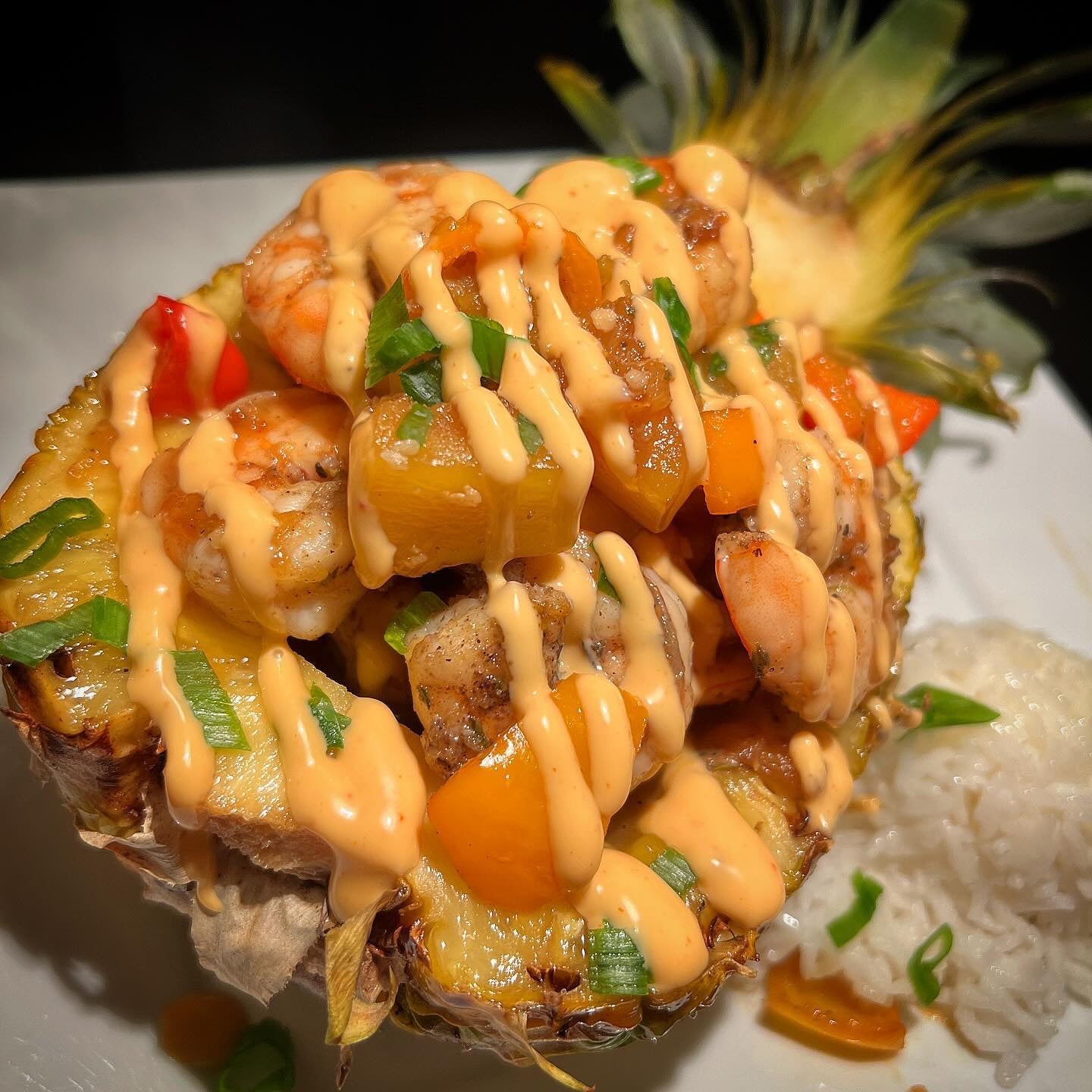 Shrimp, peppers and pineapple served in a pineapple half with rice