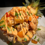 Shrimp, peppers and pineapple served in a pineapple half with rice