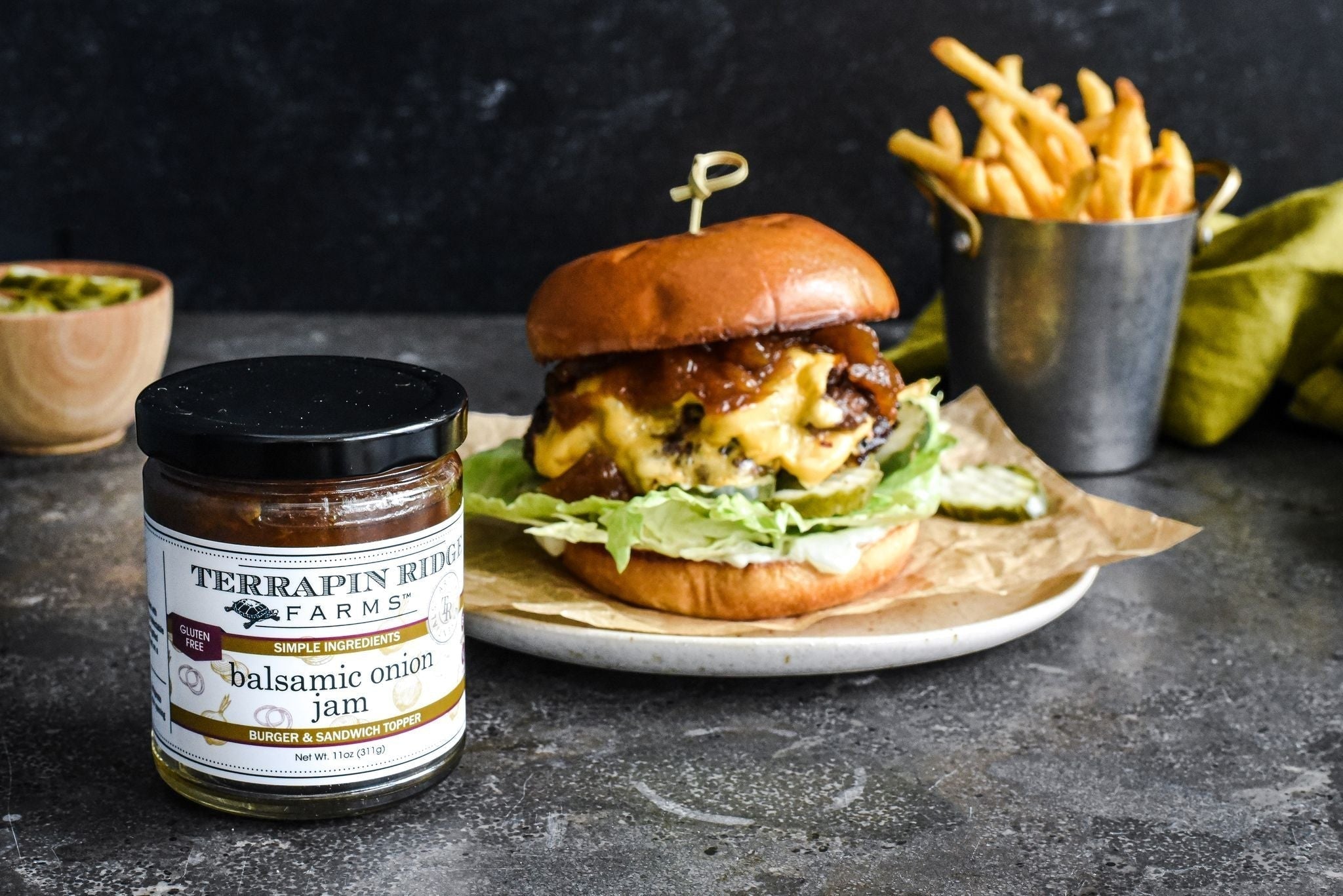 Cheeseburger and fries with a jar of Balsamic Onion Jam