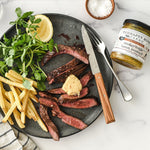 Sliced steak with fries and greens served with Smokey Maple Bacon Mustard