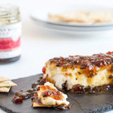 Block of cheese topped with Hot Pepper Bacon Jam served with crackers