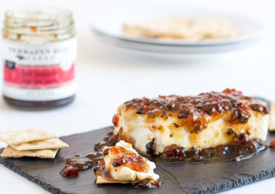 Block of cheese topped with Hot Pepper Bacon Jam served with crackers